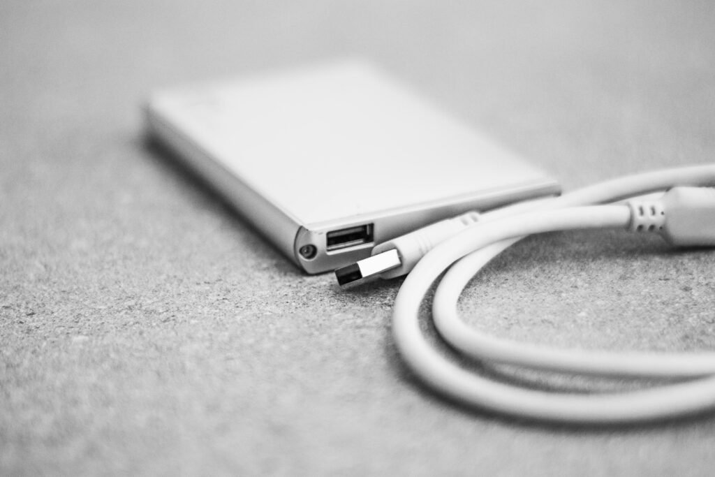 Close-up de um SSD portátil conectado via USB, representando diferentes tipos de armazenamento como DRAM less SSD vs DRAM SSD.