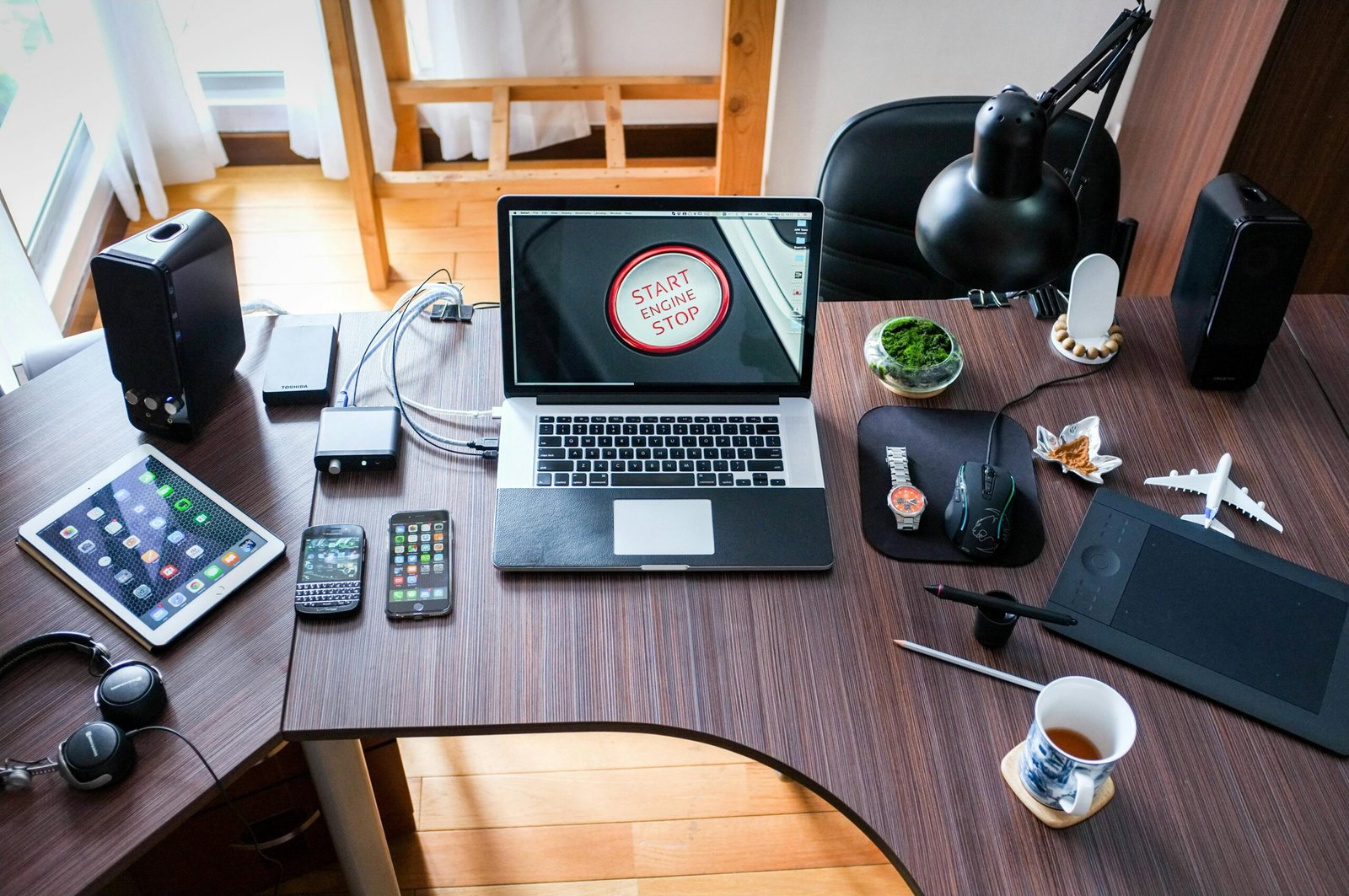 Mesa com vários smartphones, notebook e acessórios eletrônicos, ilustrando um setup tecnológico completo para trabalho, estudo ou produção de conteúdo.