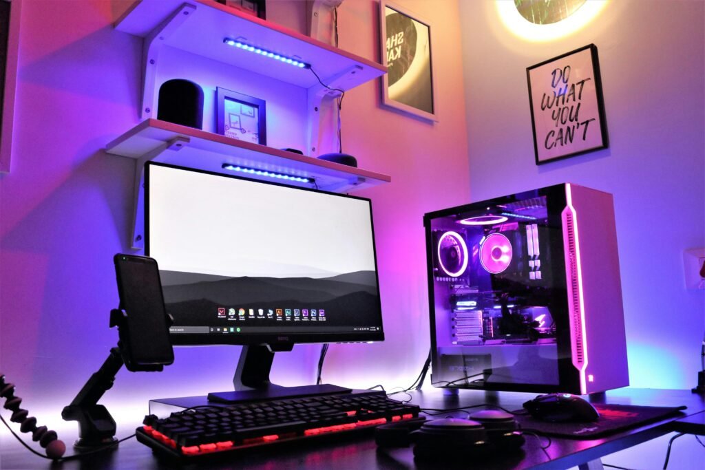 Mesa com computador, fones de ouvido e smartphone, mostrando um setup compacto e organizado para espaços pequenos.